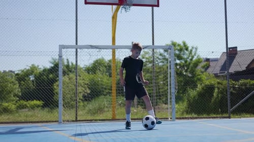 Male Teen Performing Warming Up Exercises with Soccer Ball at Local Stadium