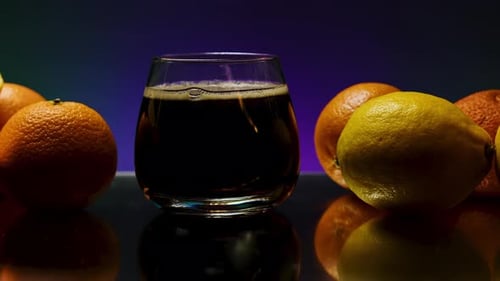 Soda bubbles in a glass against a dark wall changing colors