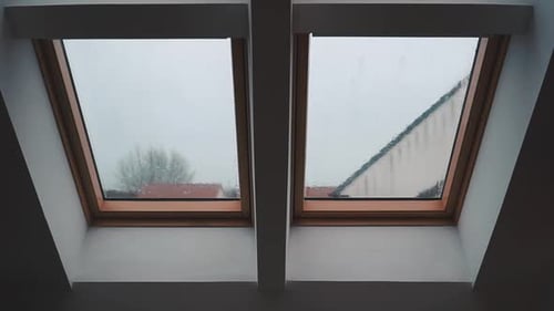 Rain falling on a loft slanted bay window on an overcast day in England in the winter