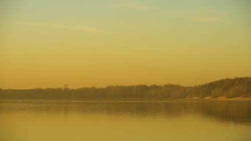 Calm and peaceful view of a lake during a yellow sunset