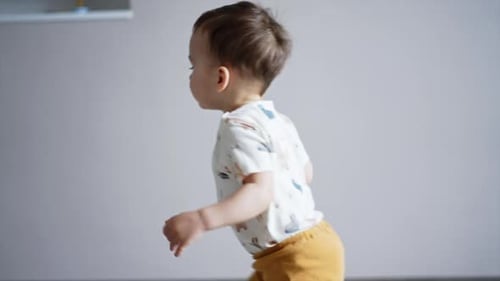 Playful active toddler crawling by the room and then stands up and runs.