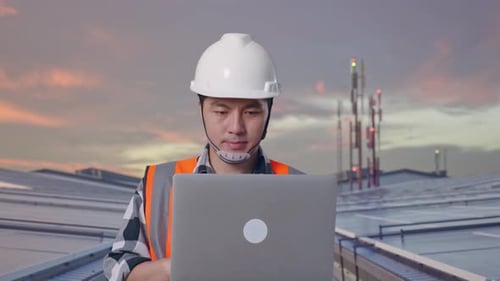 Asiatische Männer benutzen Computer, während sie auf der Dachterrasse mit Solaranlage spazieren