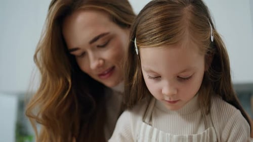 Smiling woman with child close up in kitchen