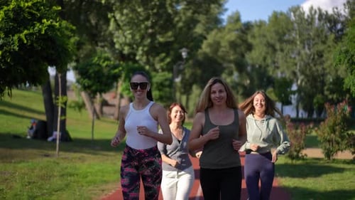 Group of Motivated Positive Sportswomen Jogging in Slow Motion on Sunny Day Outdoors