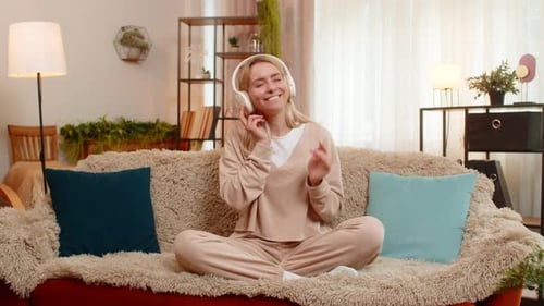 Woman Relaxes on Sofa, Listens to Music