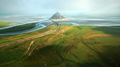 Aerial drone view of Mont-Saint-Michel in Normandy, France. Green fields, rivers and road