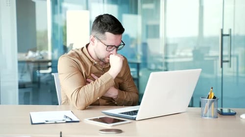 Man Coughing While Working on Laptop in Office