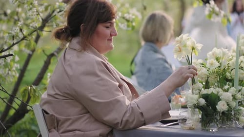 Fiesta de bodas en el jardín el día de primavera, una invitada femenina admira la decoración floral