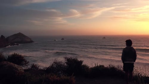 This stock video shows a man watching the sunset in a cliff over