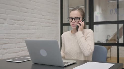 Young Woman Arguing on Phone at Office Desk
