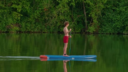 Alone Boy Floating on Stand Up Paddle Board in Lake in Summertime Standup Paddleboarding Surfer Rows