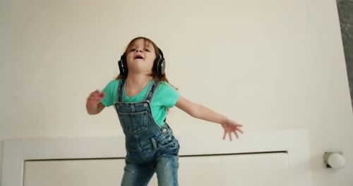 Happy Girl Dancing With Headphones in Bedroom