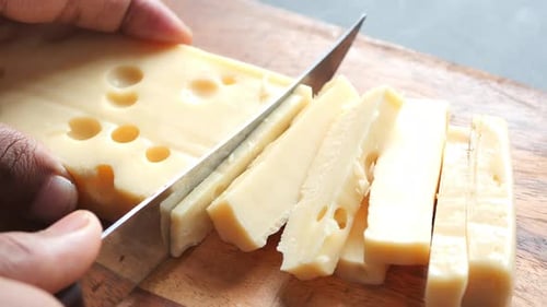 Close Up of Cutting Cheese with a Knife on a Chopping Board