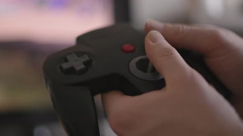 Close up of hands playing a classic 1990s video game controller
