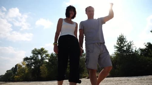 Couple Holding Hands Walking on Sandy Beach