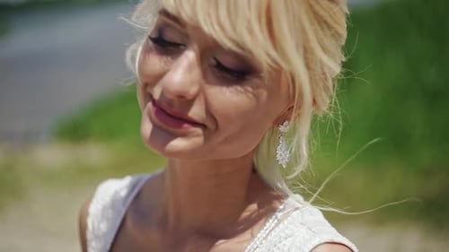 Smiling Woman in White Dress and Earrings Outdoors