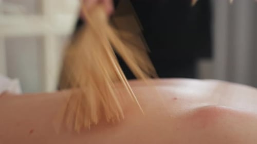 Woman Receives Massage With Bundle of Wooden Sticks