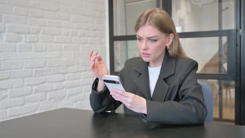 Businesswoman Shocked by Loss on Phone in Office