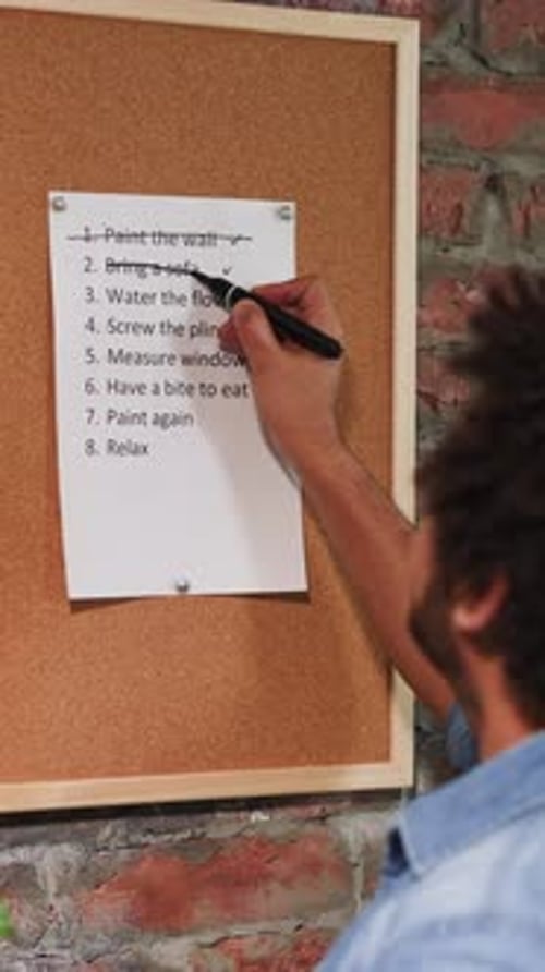 Man Crosses Out Accomplished Todo List Points in Room