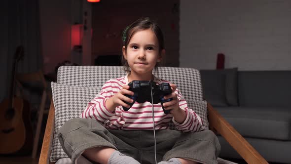 Niña jugando videojuegos sentada en un sillón en casa, Grabaciones de ...