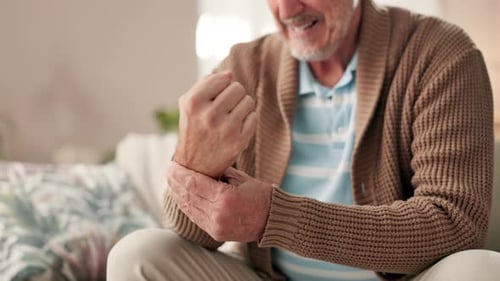Mature Man Massaging Aching Wrist in Living Room