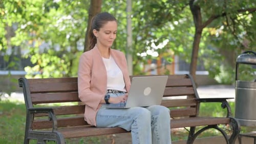Young Woman Working on Laptop while Sitting in Park