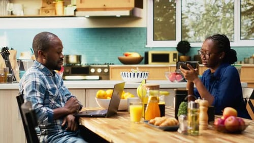 Man and Woman at Table with Laptop and Phone