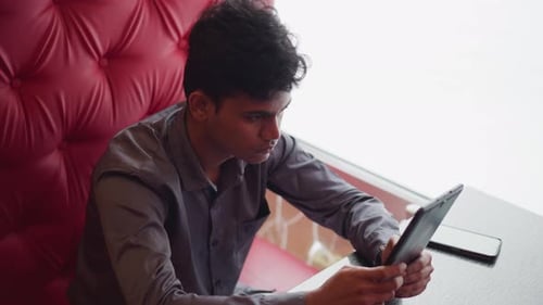 Man Uses Tablet at Table Inside