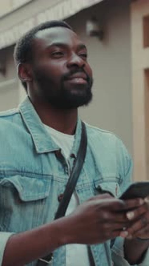 Young Man Using Mobile Phone on Street
