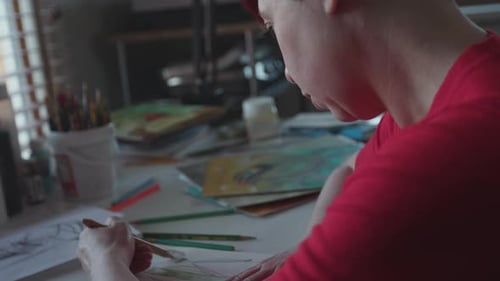 Artist Drawing in Studio Space on Artwork Surrounded by Artist'S Tools, Pencils,