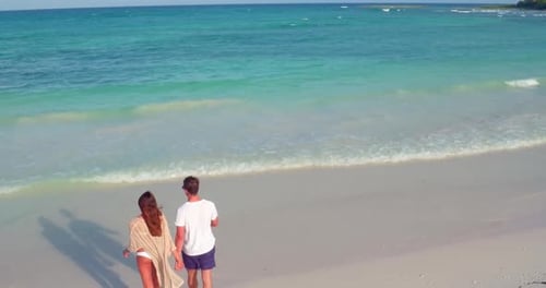 Young Couple Walks Into Waves on Tropical Beach by Aerial Drone Attractive