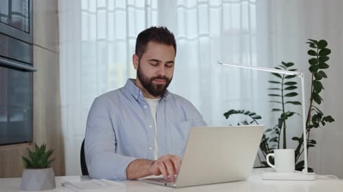 Young Man Working on Laptop at Bright Desk