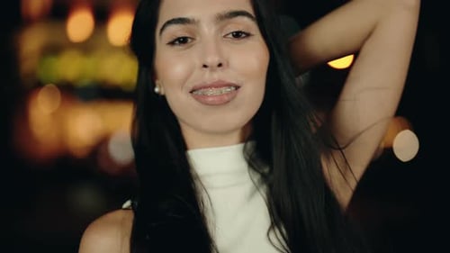 Linda jovem sorrindo e posando à noite com luzes da cidade