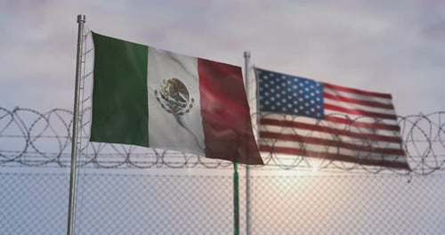 Mexico and USA Flags Waving at Barbed Wire Border Fence