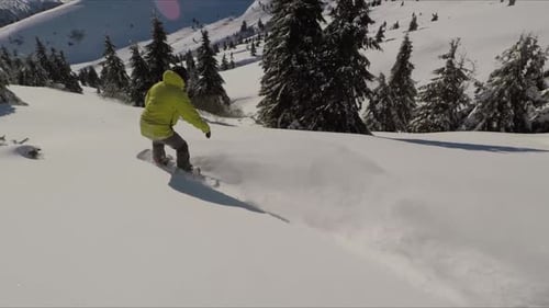 Snowboarder Carving Through Powder in Snowy Mountains