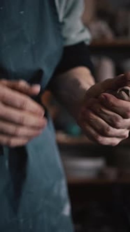 Closeup Sculptor's Hands Wet Clay with Water to Give It a Desired Shape While Working in Workshop