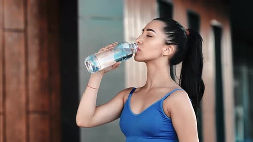 Athletic Woman Drinking Water After Exercise Outdoors