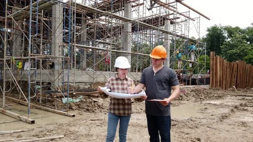 Construction manager and engineer discussing and checking plans on construction site.