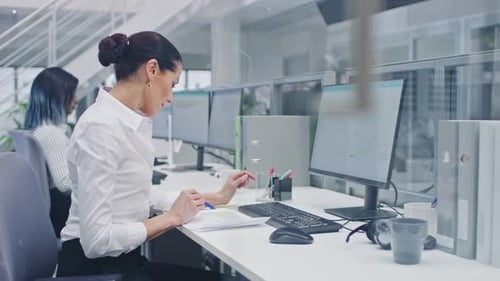 Beautiful Female Manager Works on a Desktop Computer and Compares Data on a Sheet of Paper. Diverse