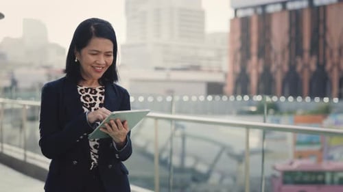 Positive Senior Investor Walking and Using Tablet for Working Purposes