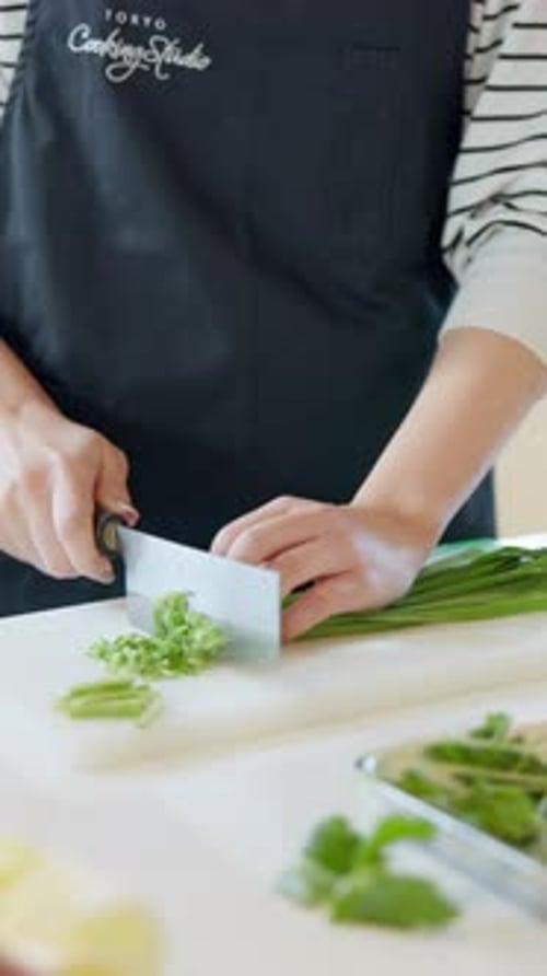 Hands Chopping Scallions in Modern Kitchen