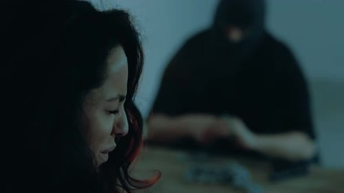 Jeune femme effrayée en pleurs assise au sous-sol le kidnappeur portant une cagoule noire dans le