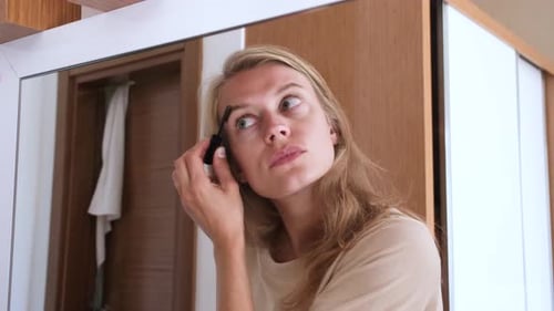 Beautiful woman making up by the mirror in hotel room