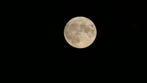 Full harvest moon crater glowing surface closeup passing across dark sky