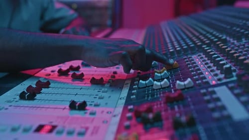 Hand of African American Sound Engineer Leveling Consoles