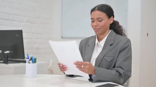 Businesswoman Reviews Documents with a Smile in Office
