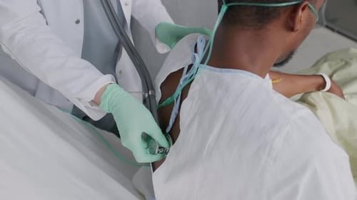 Doctor Examines Patient with Stethoscope in Hospital Bed