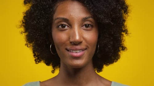 Woman Smiling with Curly Hair on Yellow Background