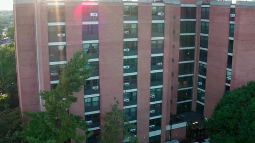 Residential apartment building. Tall brick building. Rising aerial reveals urban city in USA at suns