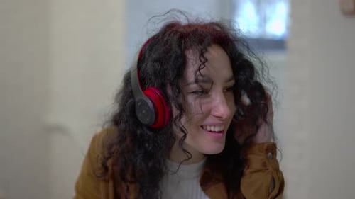 Closeup Portrait of Happy Relaxed Woman Listening to Music in Headphones Sitting in Cafe Front View